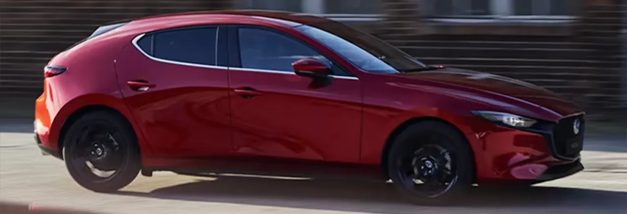 Une Mazda 3 rouge roule sur une route