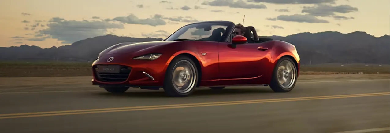 La Mazda MX-5 rouge roule au coucher du soleil
